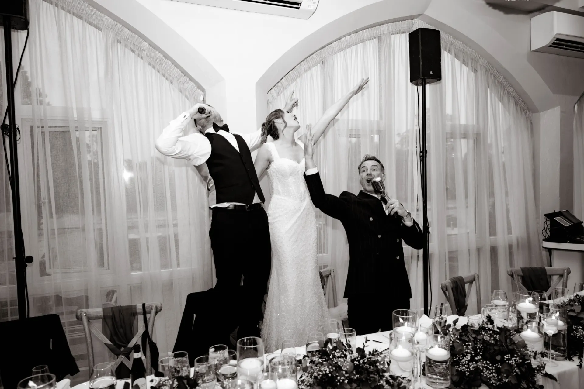 A wedding breakfast table mid-laughter, everyone on their feet