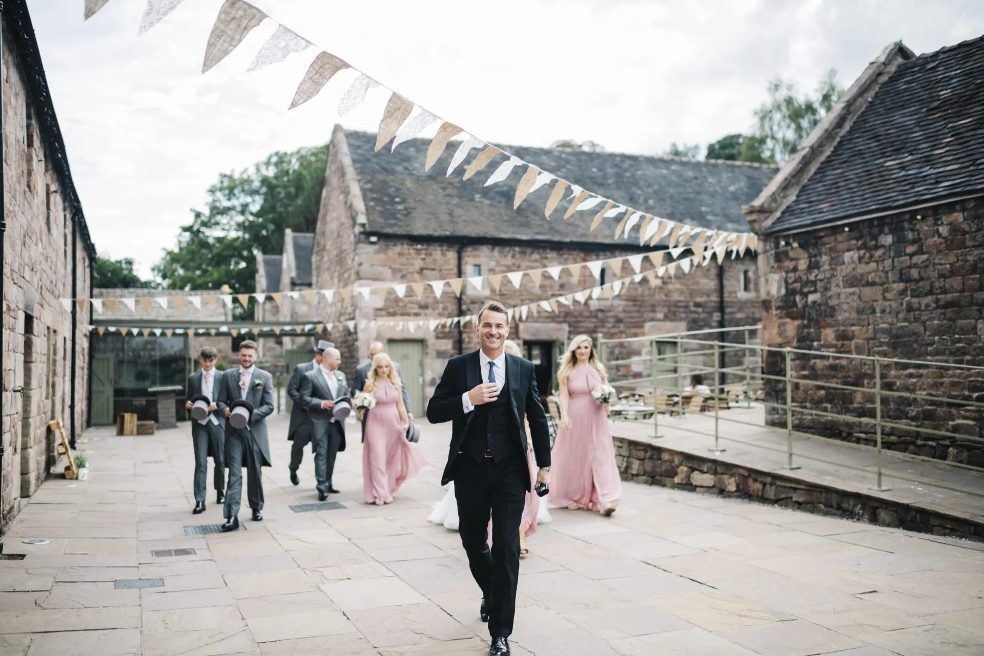 A couple walking through a stone courtyard strung with bunting on their wedding day