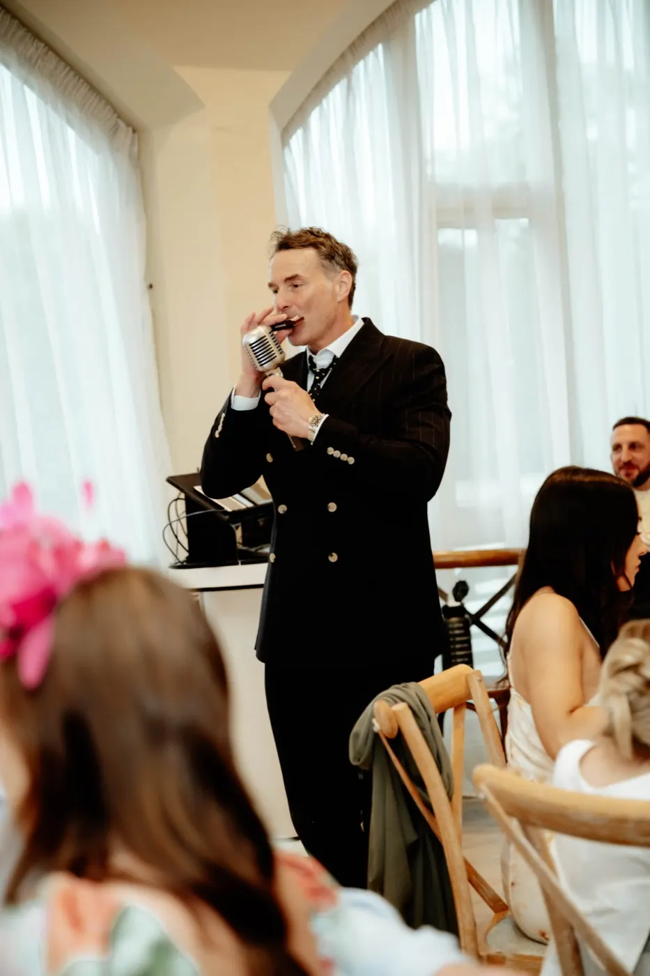 Howard Wing singing by the tall windows at a wedding