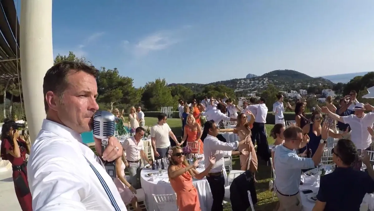Howard mid-song on an Ibiza terrace, the party dancing below