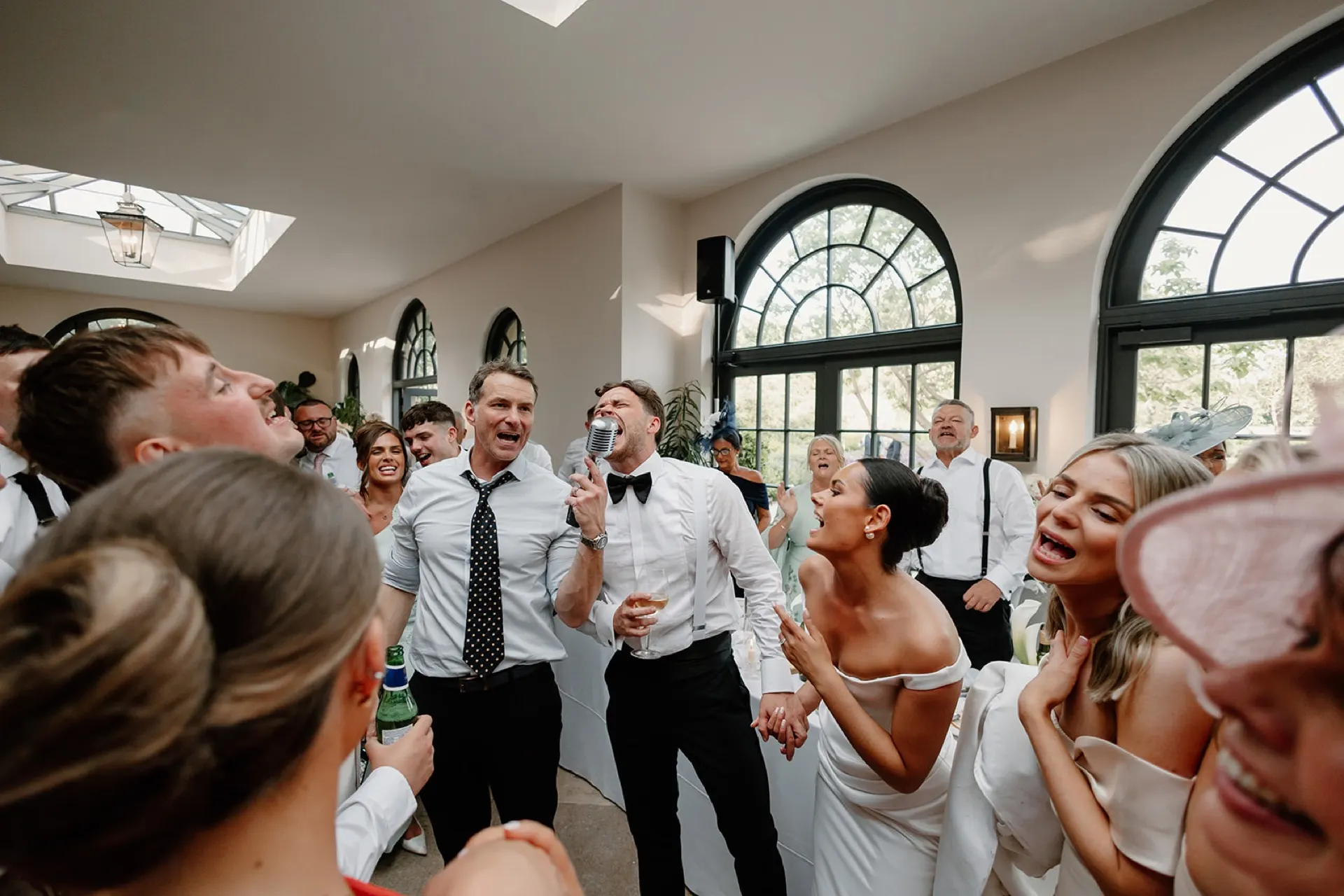 A wedding crowd under the skylight, everyone singing