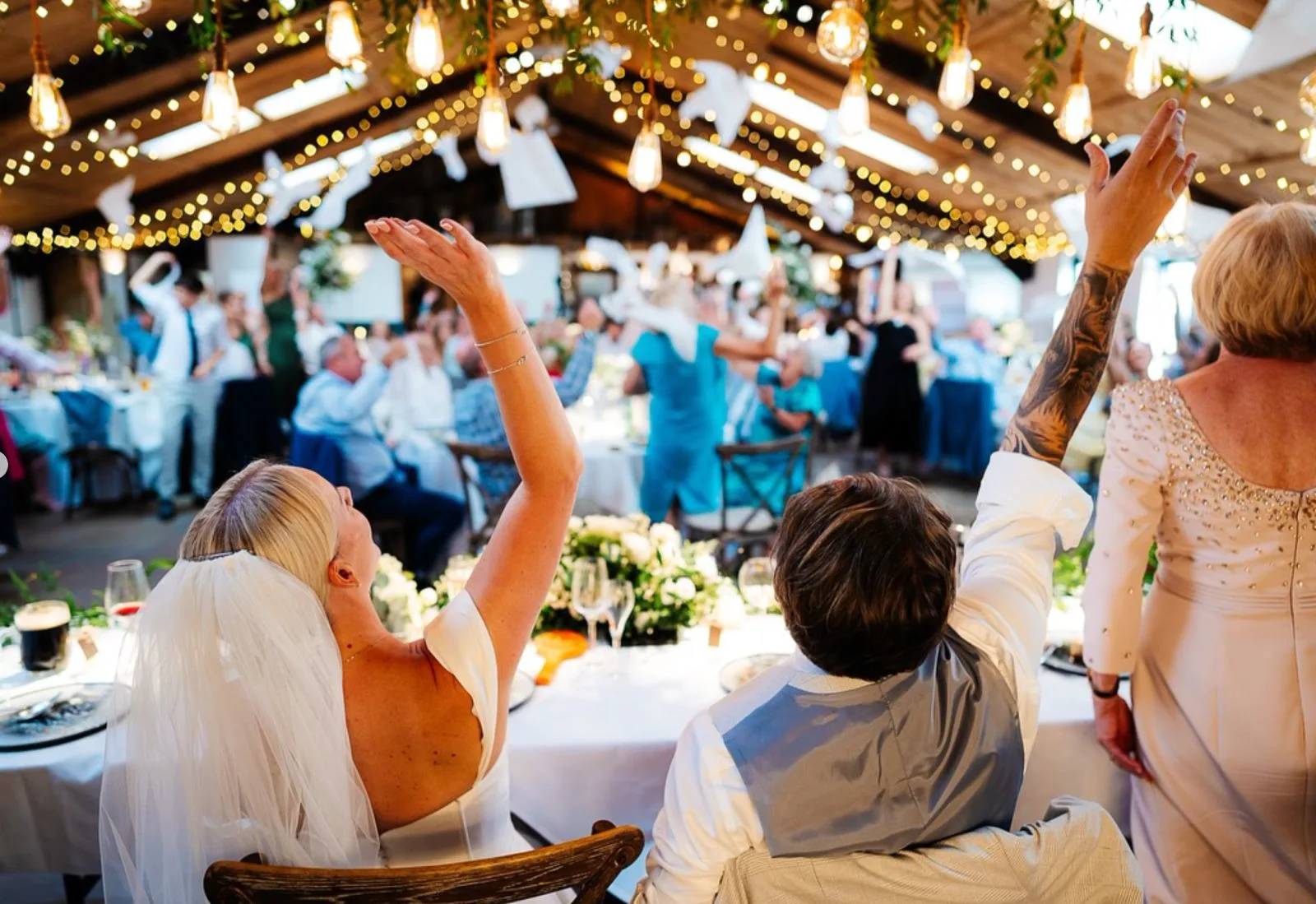 Alex on her feet at the top table at Owen House Barn, every hand in the room up