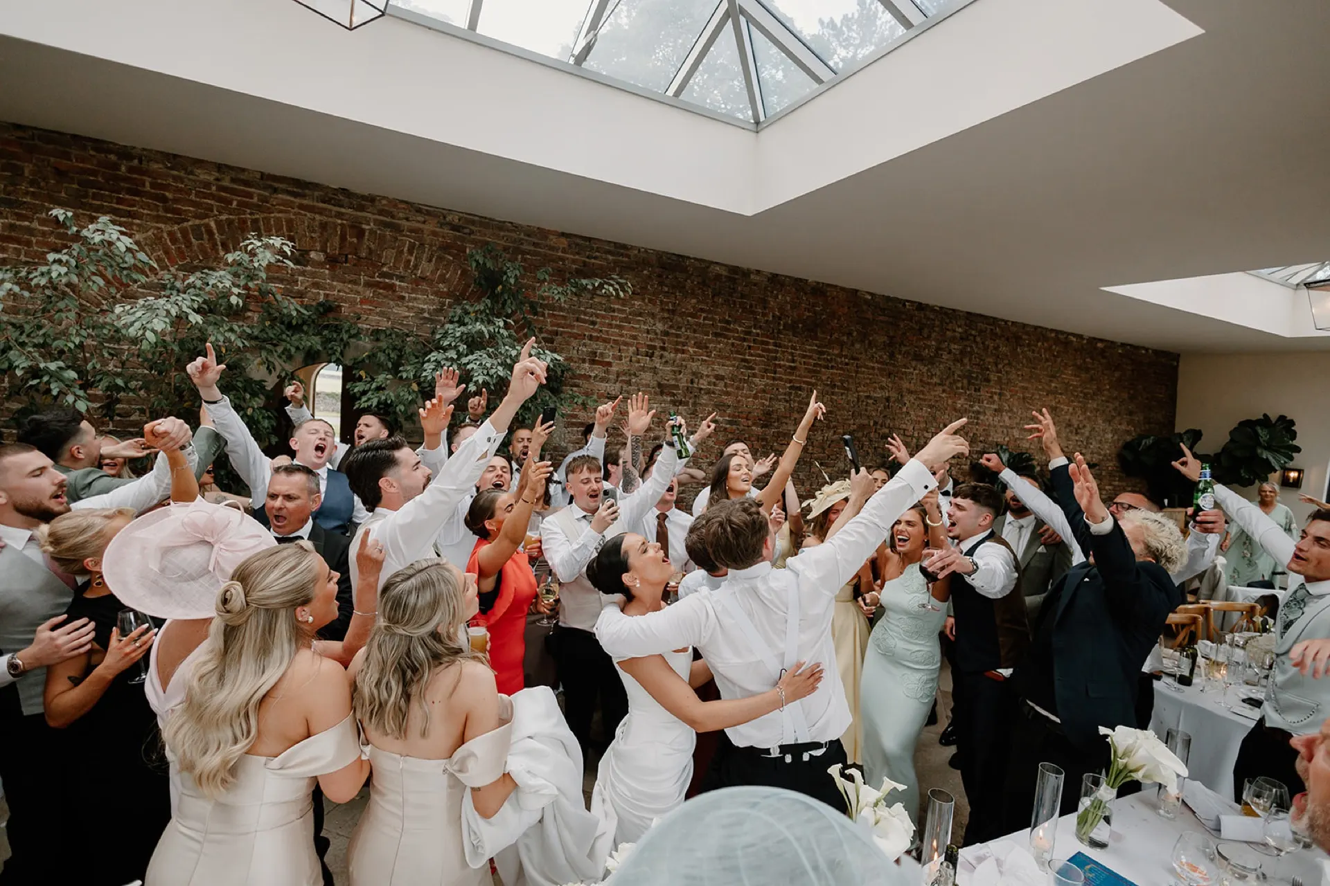 A whole wedding room with every hand in the air
